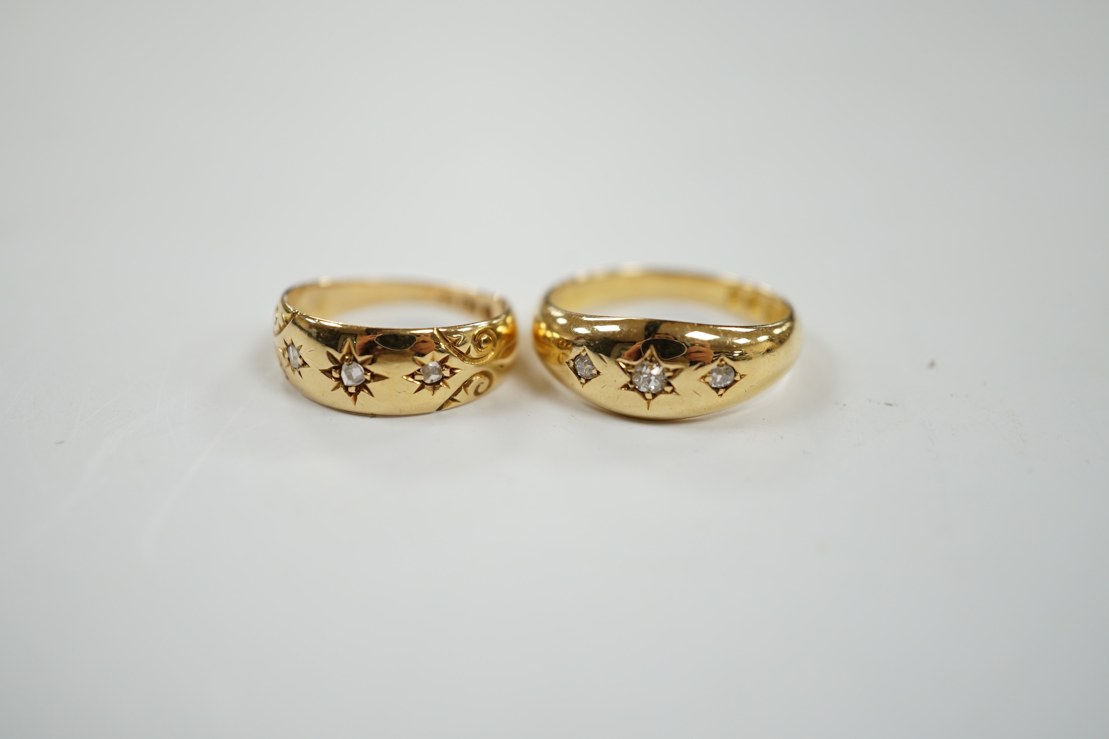 A late Victorian 18ct gold and gypsy set three stone diamond ring, size M and a similar smaller ring, size H, gross weight 8.1 grams. Condition - good